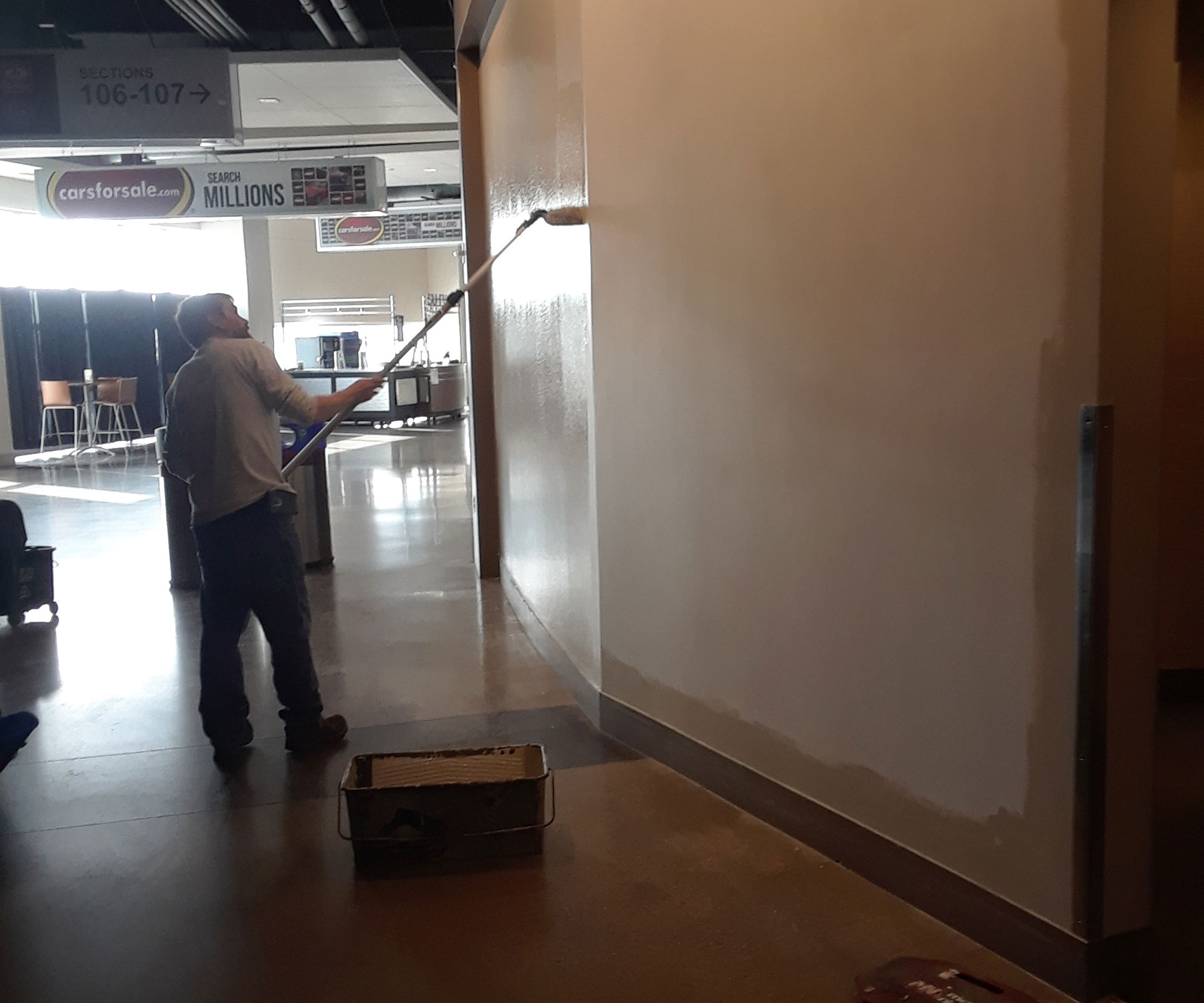 Cornerstone painter rolling a fresh coat onto a concourse wall inside a commercial venue