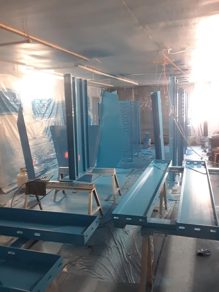 Steel finish-coated in blue inside a fully masked spray room.